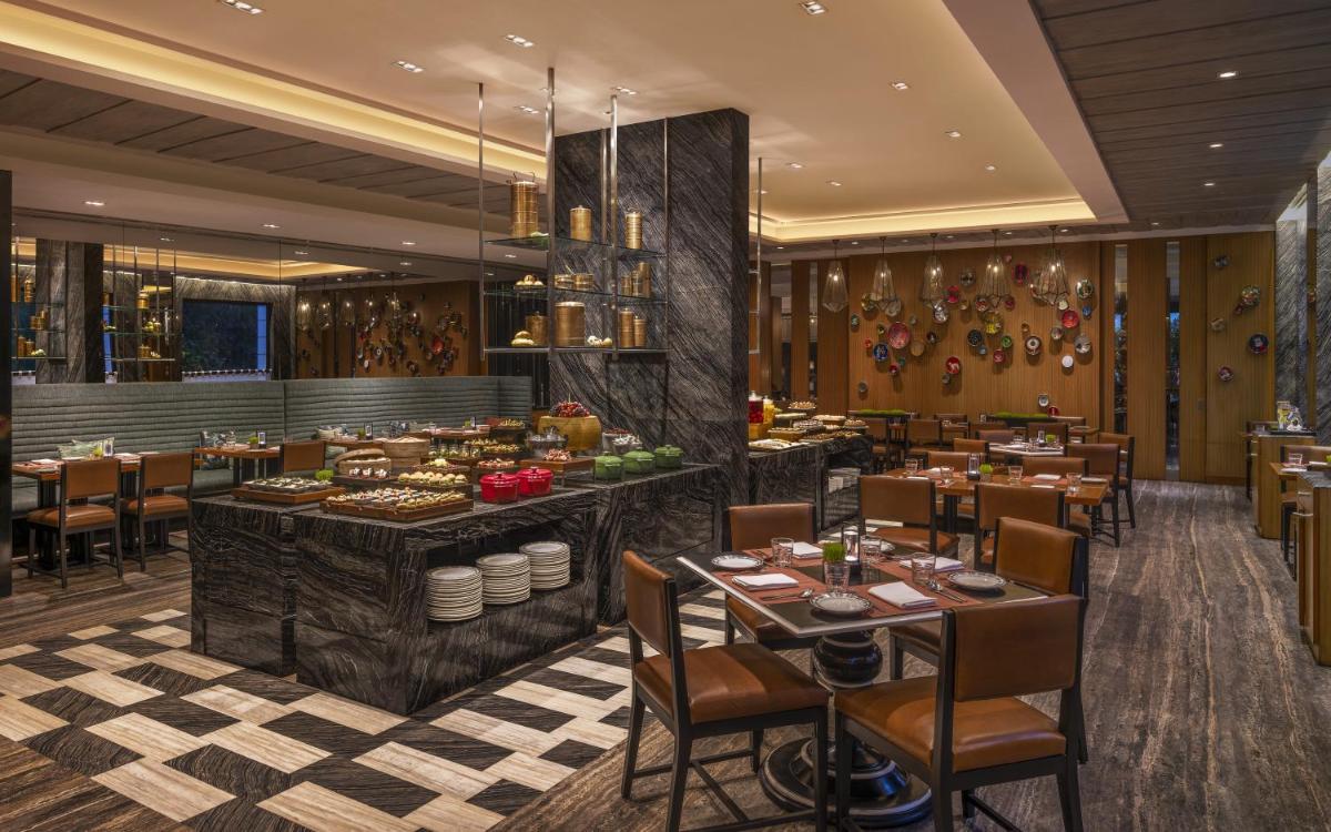 a restaurant with tables and chairs in a room at The Raintree, St. Mary’s Road in Chennai