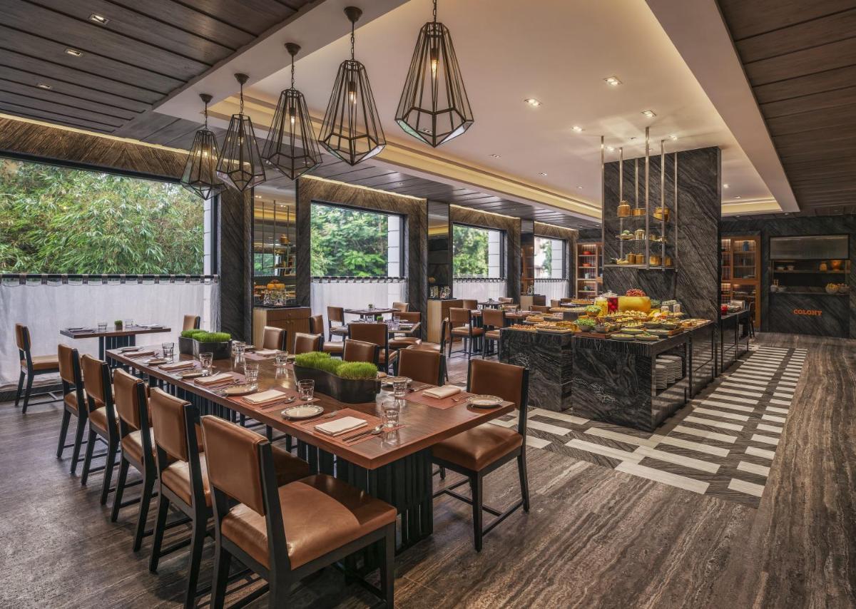 a dining room with a long table and chairs at The Raintree, St. Mary’s Road in Chennai