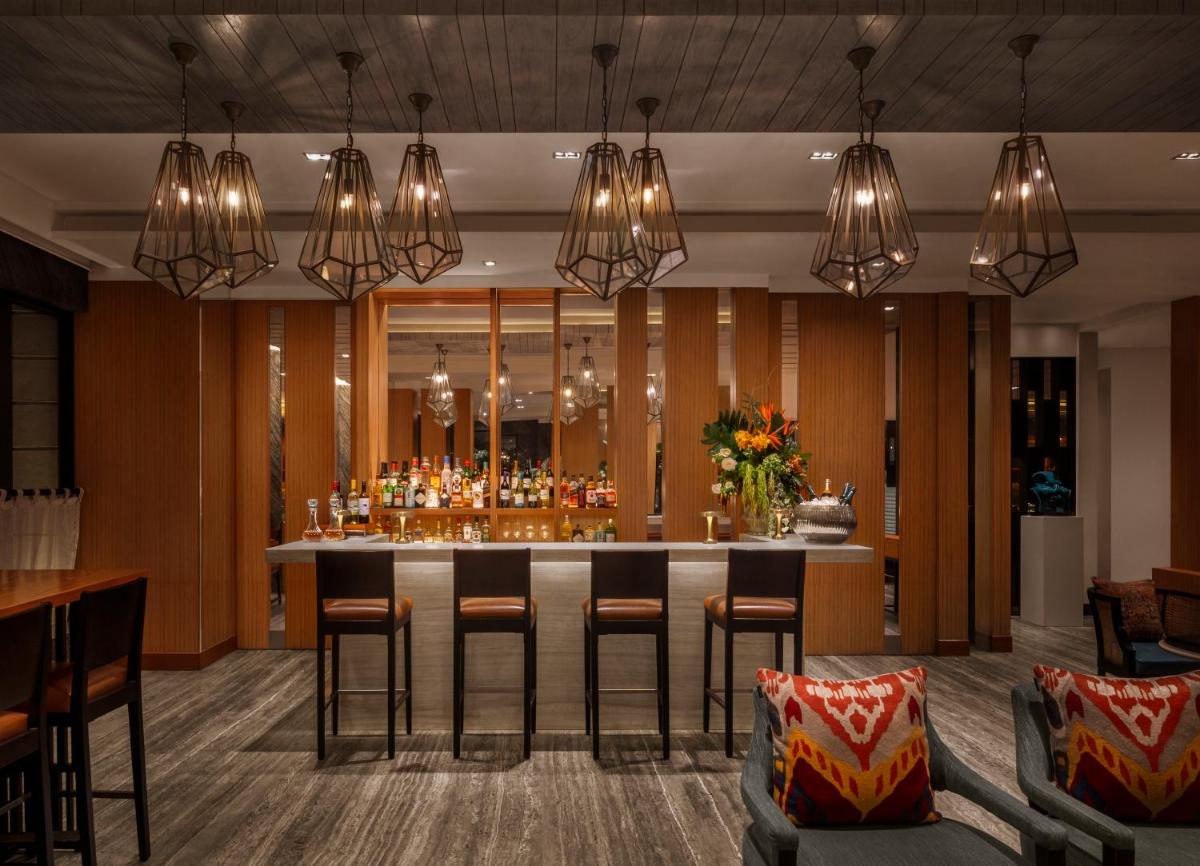a bar in a hotel lobby with chandeliers at The Raintree, St. Mary’s Road in Chennai