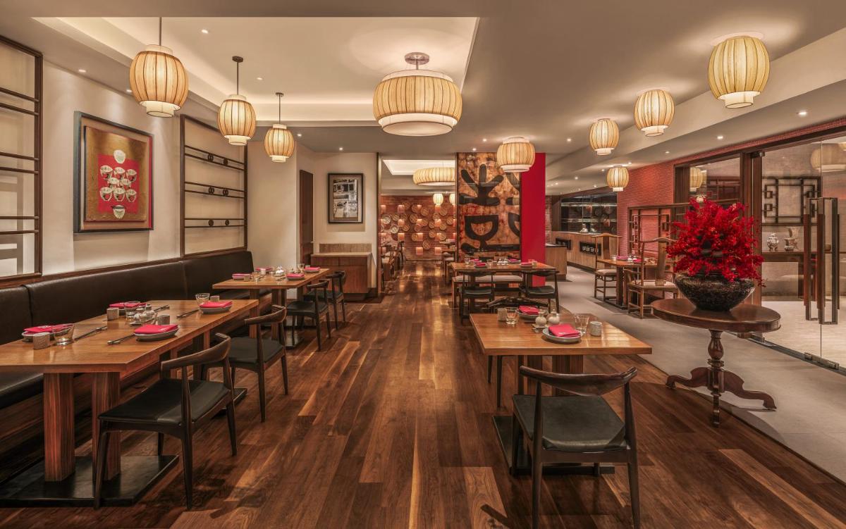 a restaurant with wooden tables and chairs and chandeliers at The Raintree, St. Mary’s Road in Chennai