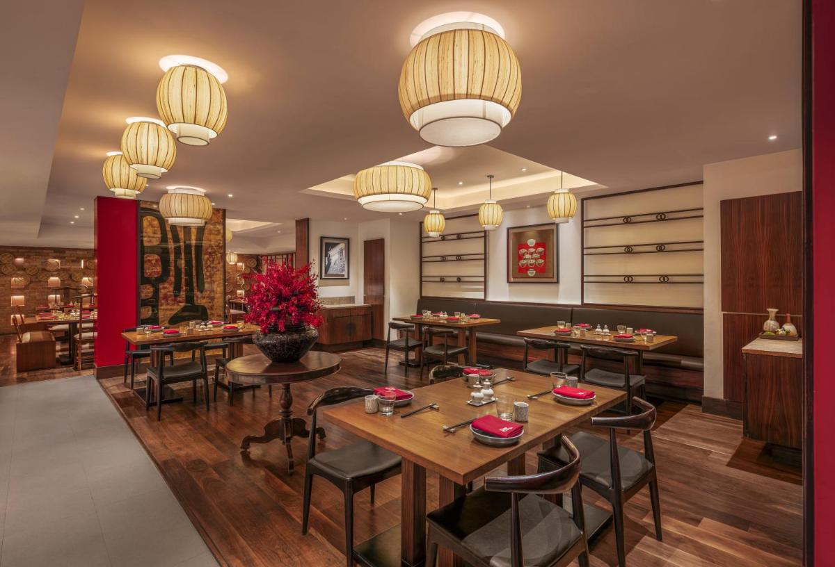 a restaurant with tables and chairs and chandeliers at The Raintree, St. Mary’s Road in Chennai
