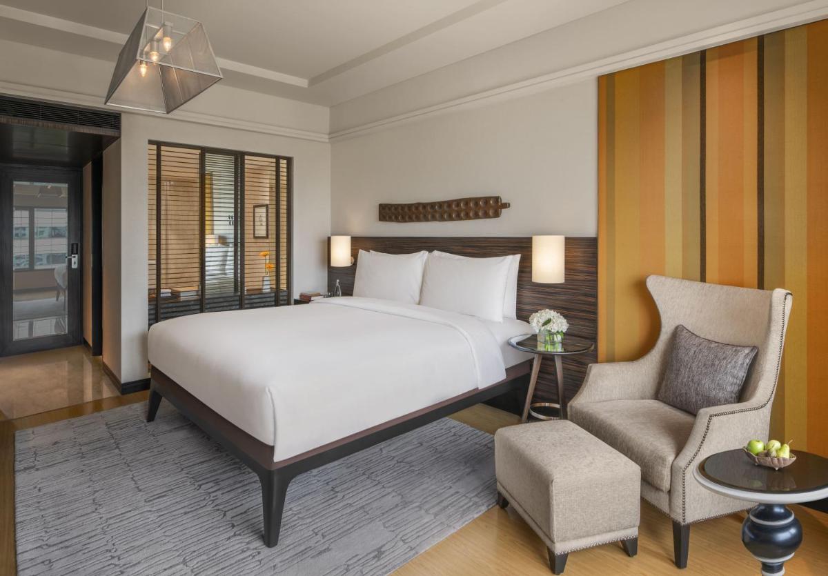 a bedroom with a large bed and a chair at The Raintree, St. Mary’s Road in Chennai