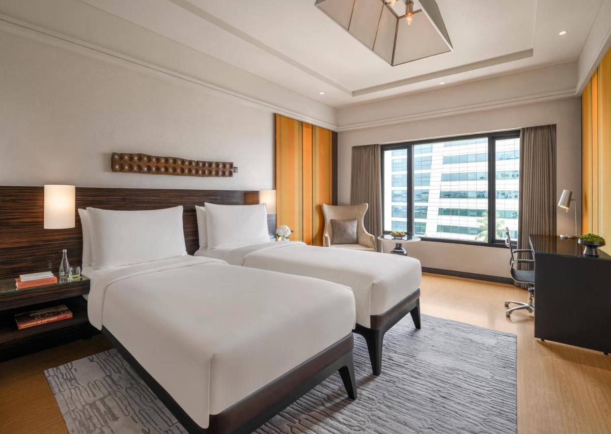 a hotel room with two beds and a television at The Raintree, St. Mary’s Road in Chennai