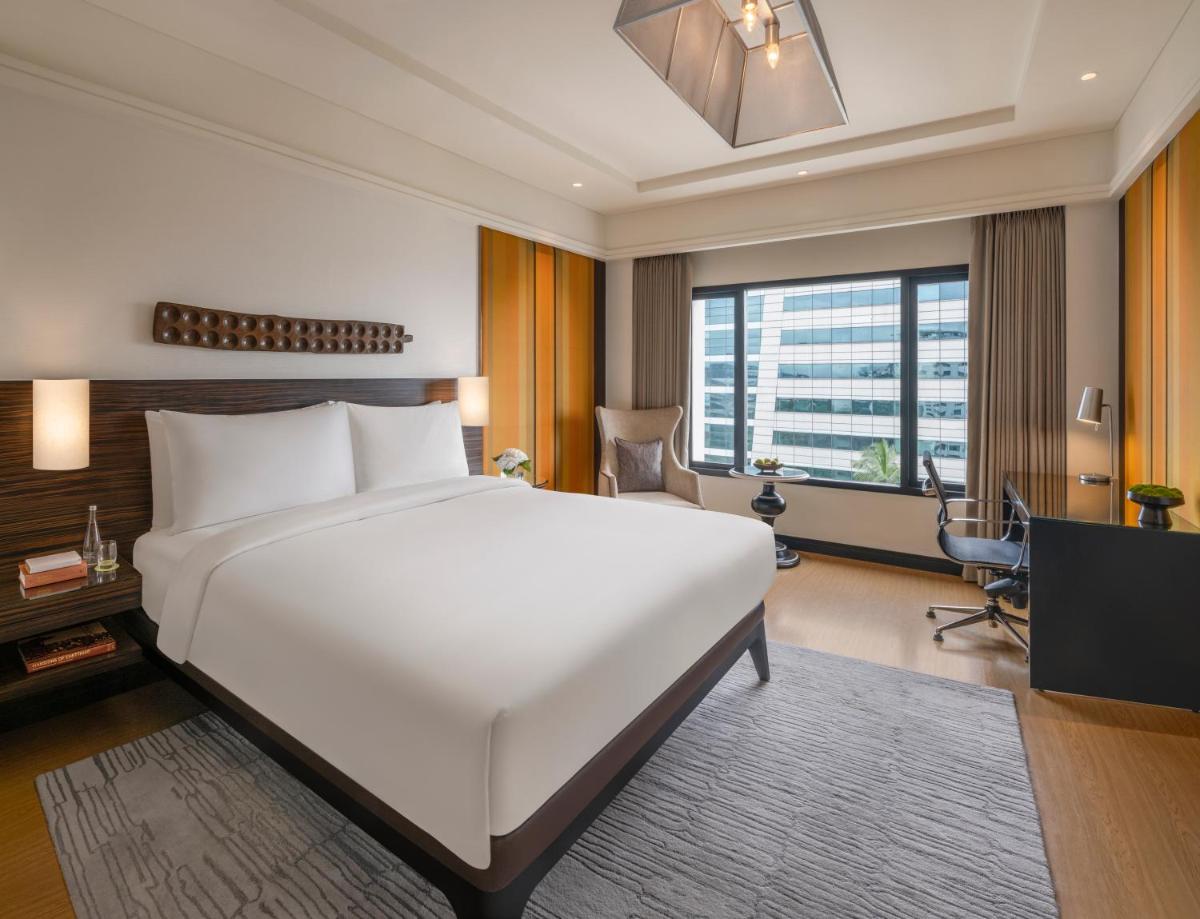 a bedroom with a large white bed and a desk at The Raintree, St. Mary’s Road in Chennai