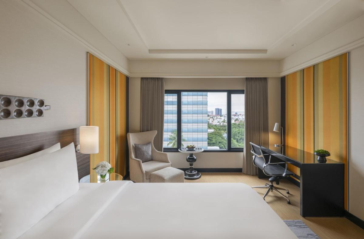 a bedroom with a bed and a desk and a chair at The Raintree, St. Mary’s Road in Chennai