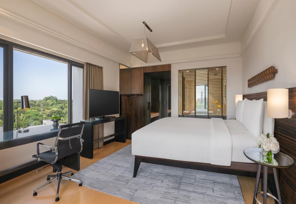 a bedroom with a bed and a desk and a tv at The Raintree, St. Mary’s Road in Chennai