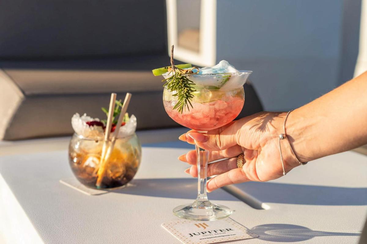 uma pessoa segurando um coquetel em um copo sobre uma mesa em Jupiter Lisboa Hotel - Rooftop & Spa em Lisboa