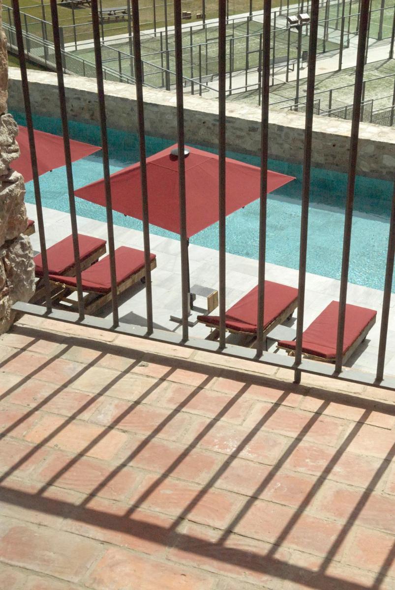 Tres sillas en una piscina detrás de una valla en Hotel Boutique Puig Francó - Adults Only, en Camprodon