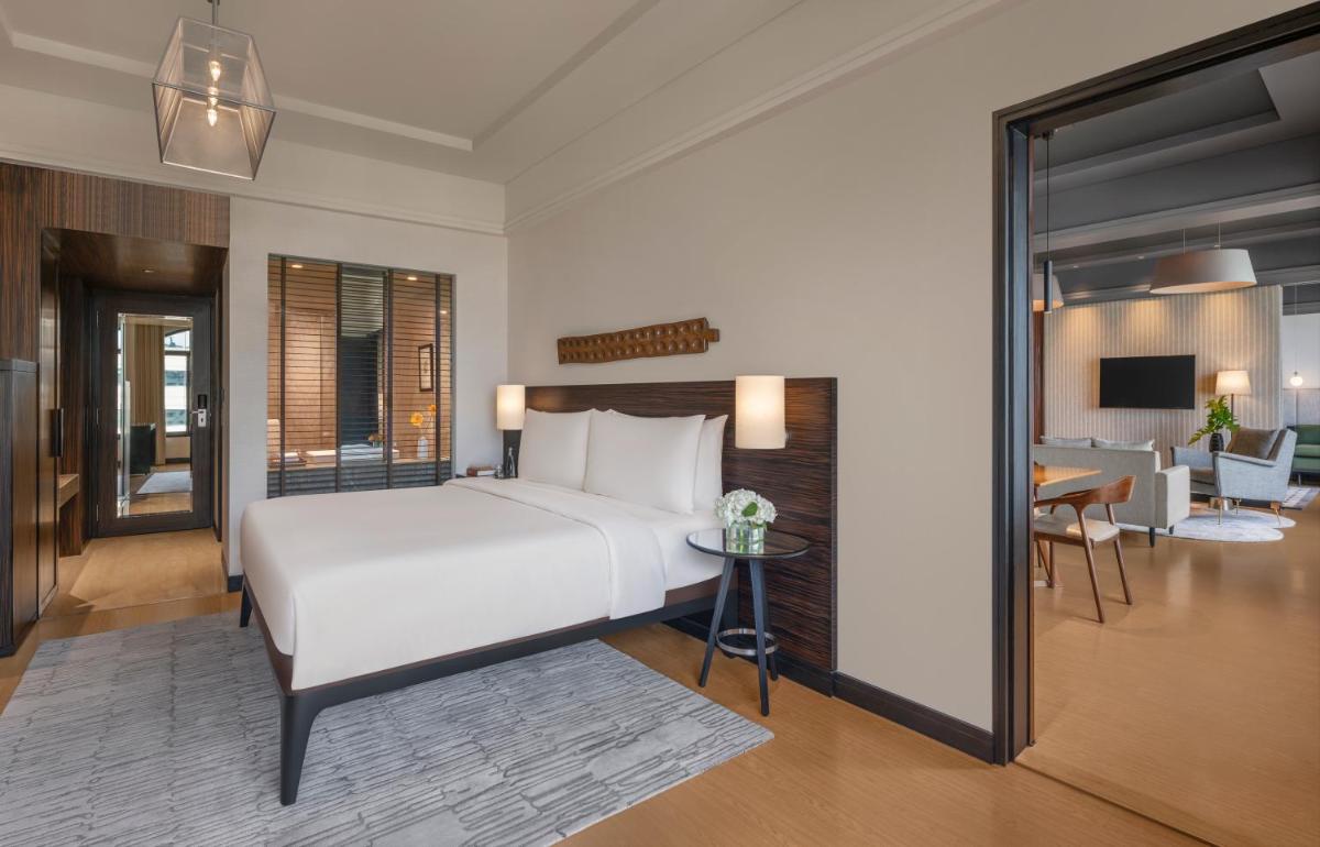 a bedroom with a large bed and a living room at The Raintree, St. Mary’s Road in Chennai