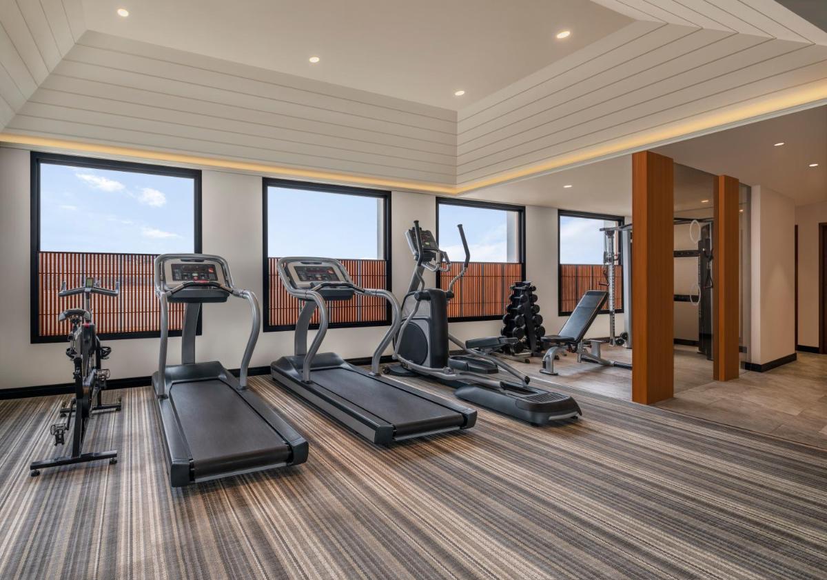 a gym with treadmills and ellipticals in a room with windows at The Raintree, St. Mary’s Road in Chennai