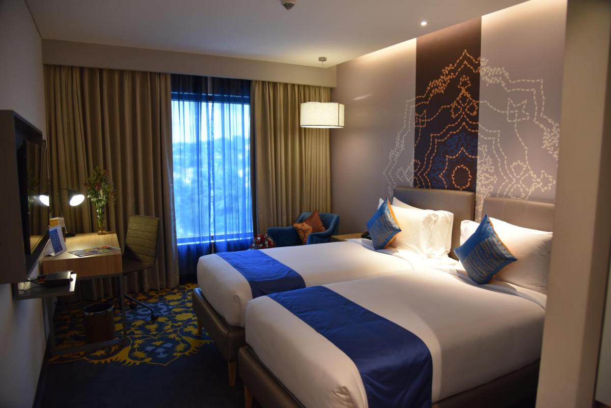 a hotel room with two beds and a window at Grand Mercure Mysore - An Accor Brand in Mysore