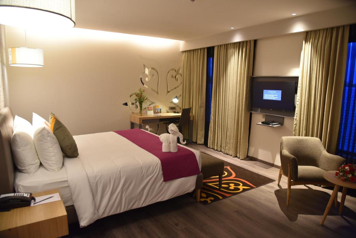 a hotel room with a bed with a teddy bear on it at Grand Mercure Mysore - An Accor Brand in Mysore