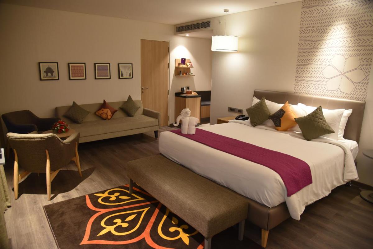 a bedroom with a large bed and a couch at Grand Mercure Mysore - An Accor Brand in Mysore