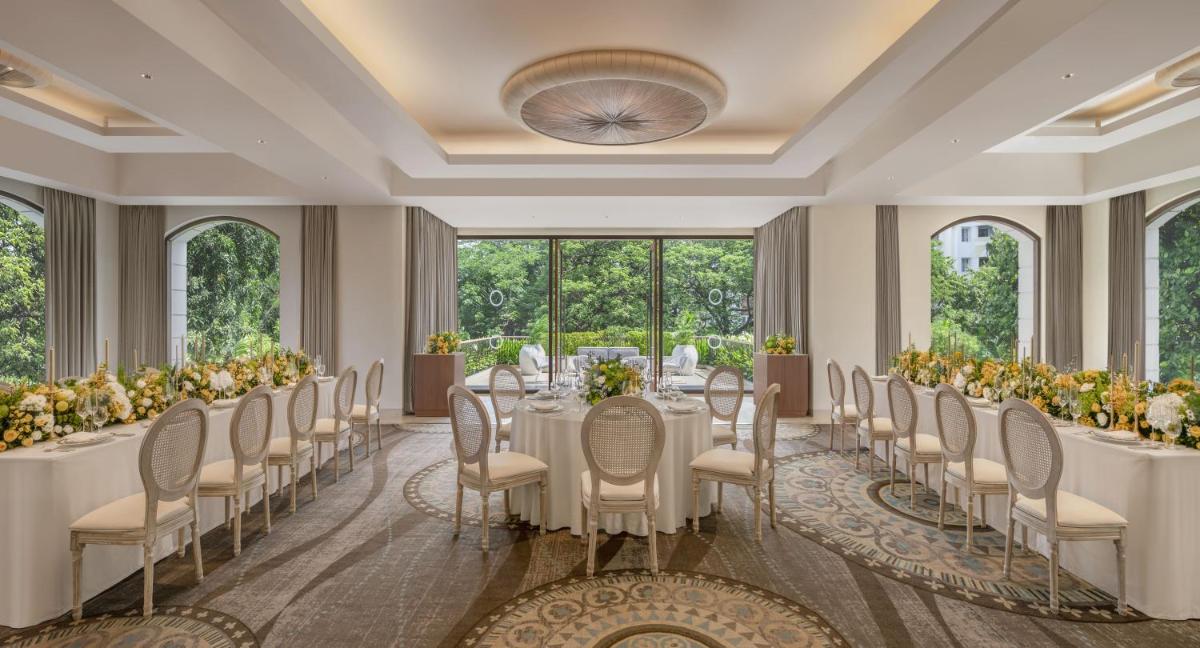 a banquet hall with white tables and chairs and windows at The Raintree, St. Mary’s Road in Chennai