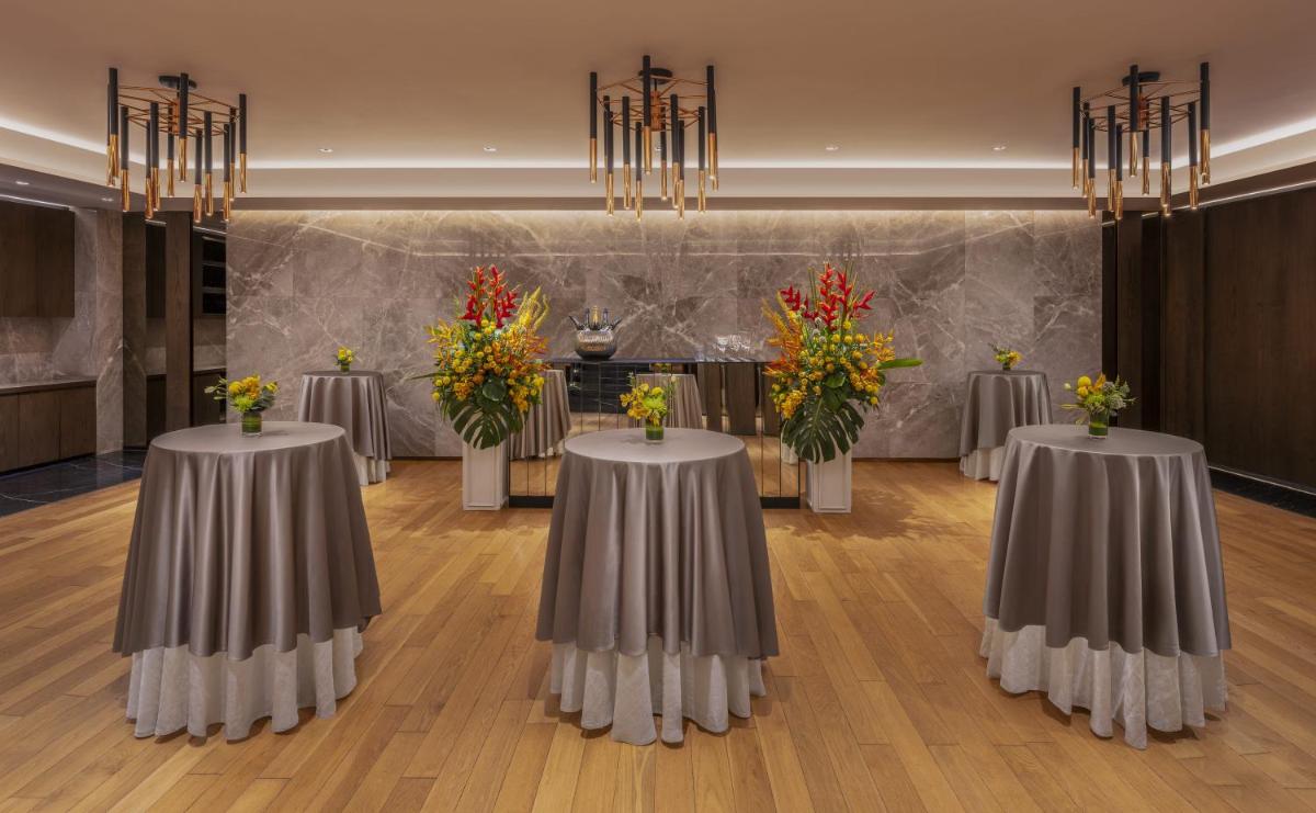 a conference room with three tables with flowers on them at The Raintree, St. Mary’s Road in Chennai