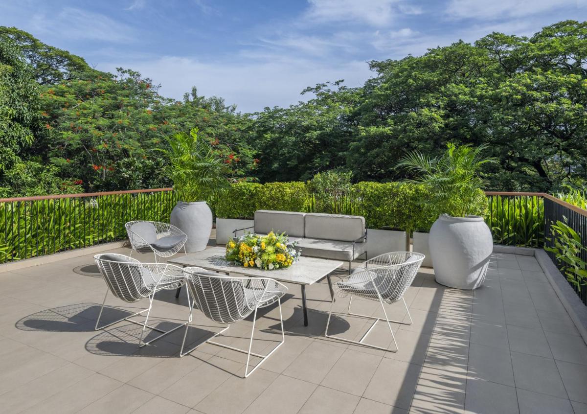 a patio with a table and chairs and trees at The Raintree, St. Mary’s Road in Chennai