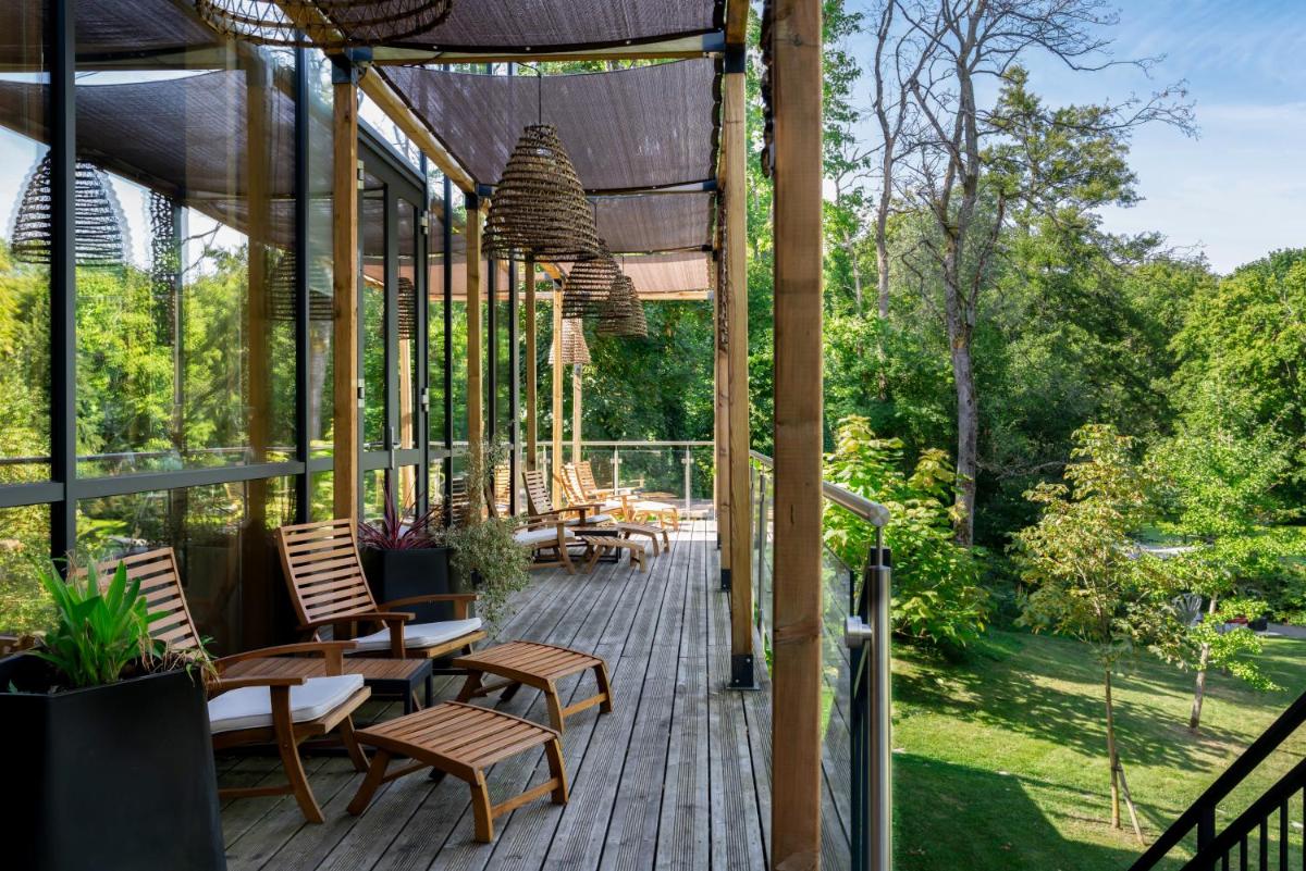 une terrasse en bois avec des chaises et des tables. dans l'établissement Domaine de la Résidence - Hôtel, Spa & Restaurant, à Moulins-lès-Metz