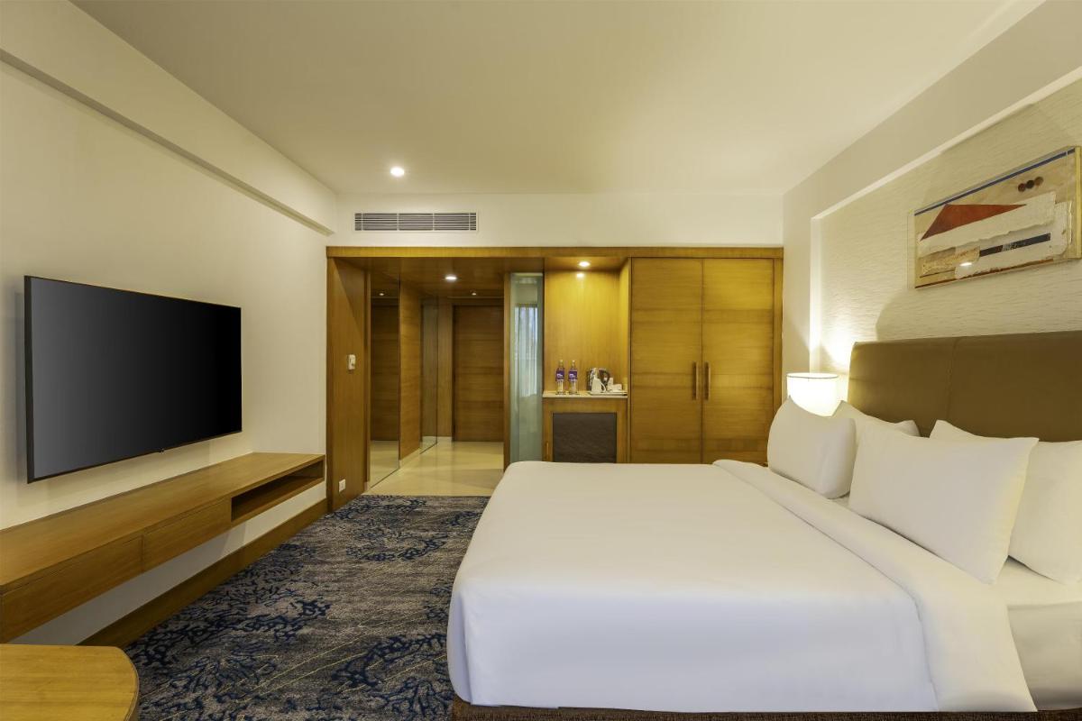a hotel room with a bed and a flat screen tv at Radisson Blu Hotel Pune Kharadi in Pune