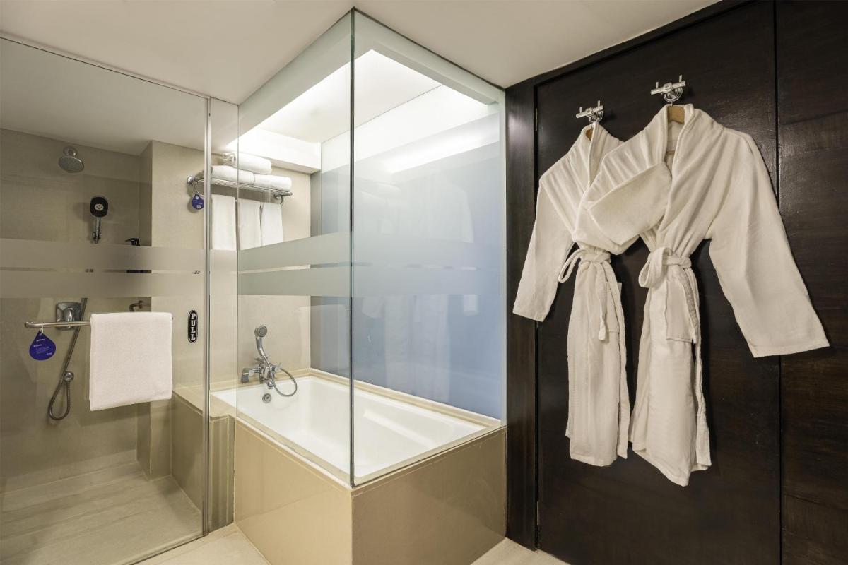 a bathroom with a shower and a robe hanging on a door at Radisson Blu Hotel Pune Kharadi in Pune