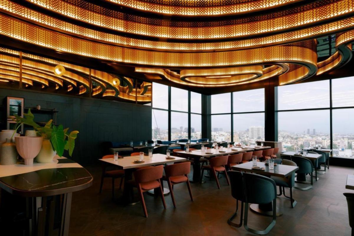 a restaurant with tables and chairs under a large chandelier at Radisson Blu Hotel Pune Kharadi in Pune