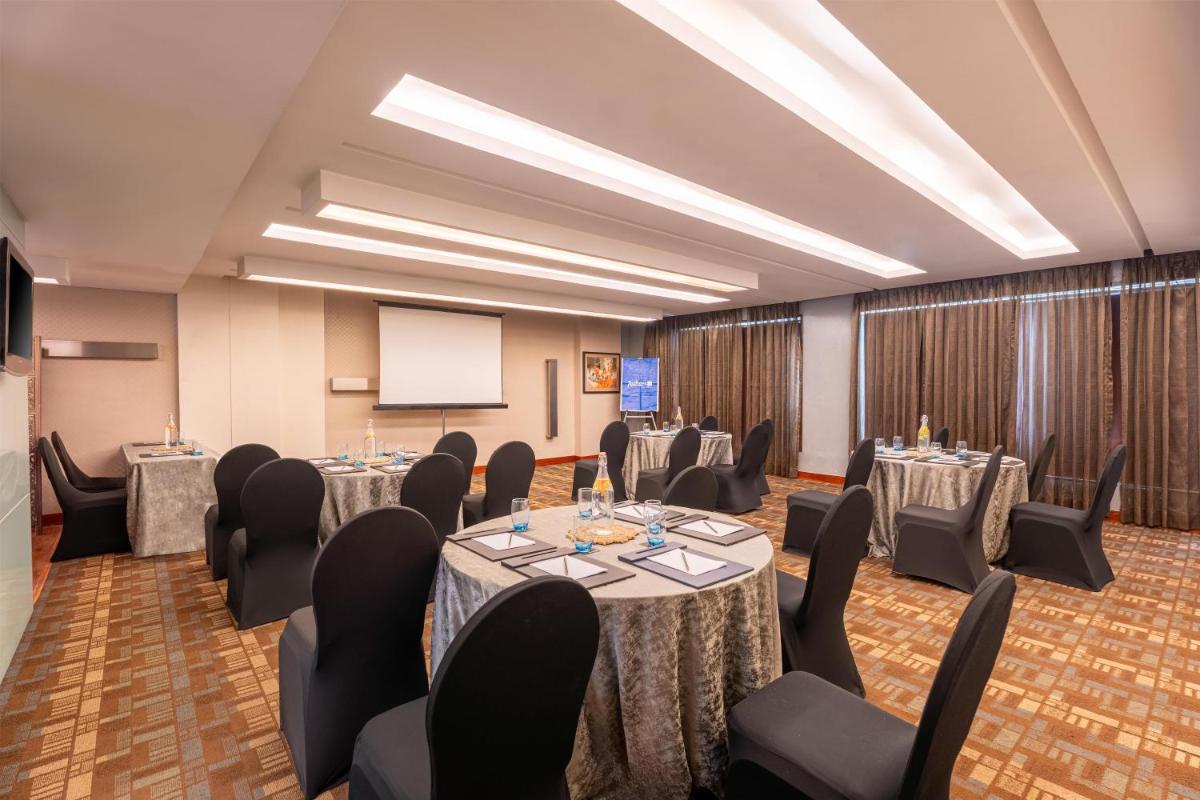 a conference room with tables and chairs and a screen at Radisson Blu Hotel Pune Kharadi in Pune