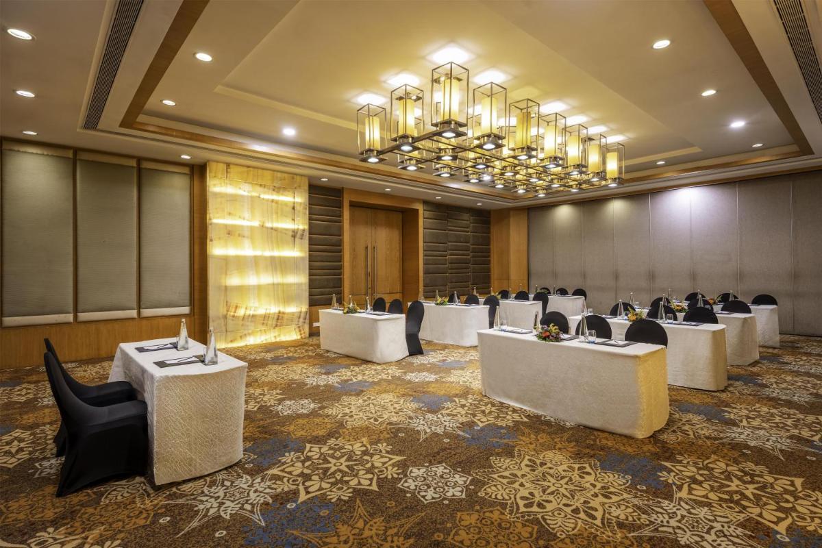 a conference room with tables and chairs and a chandelier at Radisson Blu Hotel Pune Kharadi in Pune