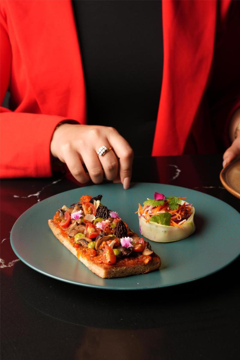 a person sitting at a table with a plate of pizza at Radisson Blu Hotel Pune Kharadi in Pune