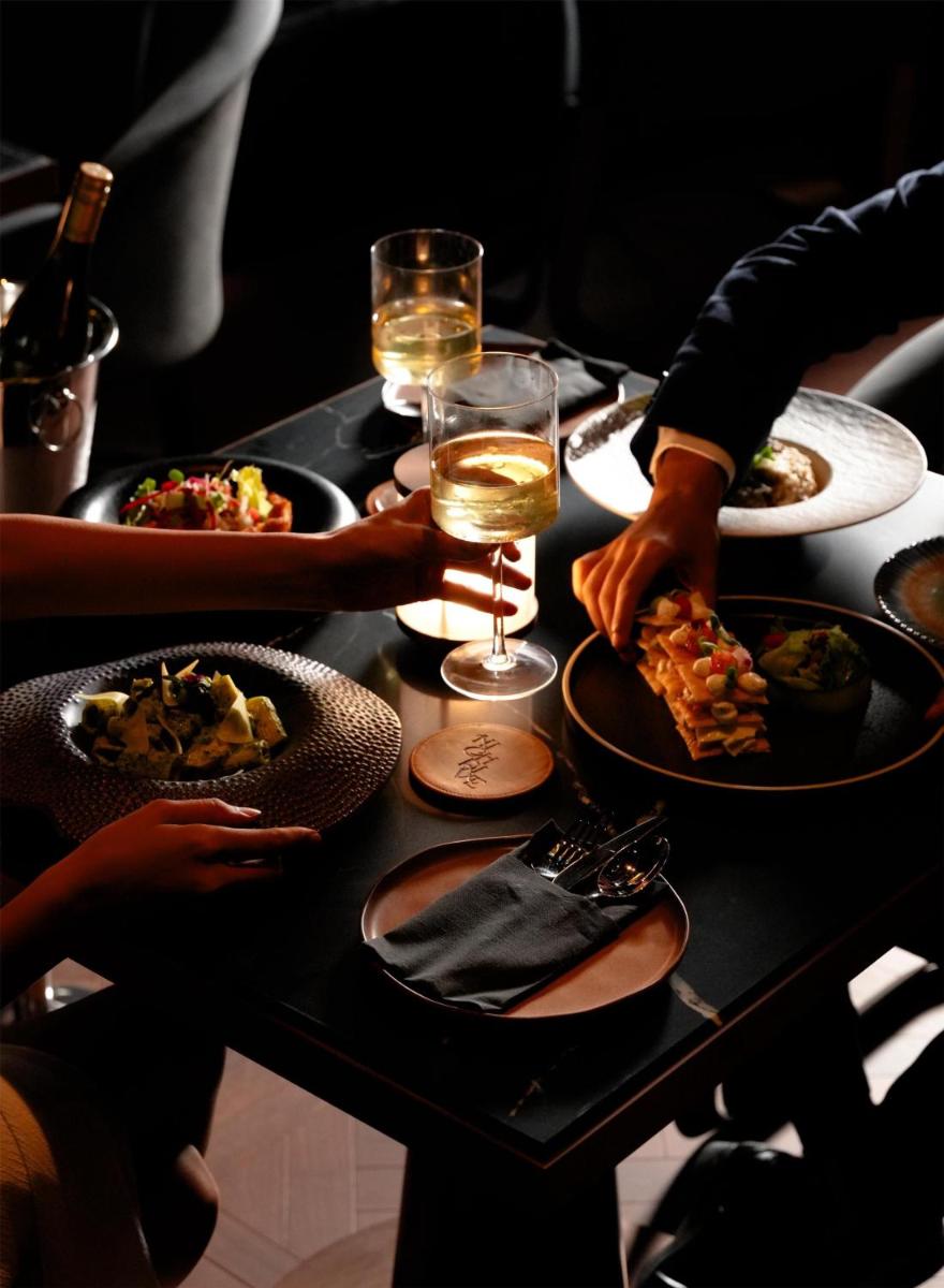a table with plates of food and a glass of wine at Radisson Blu Hotel Pune Kharadi in Pune