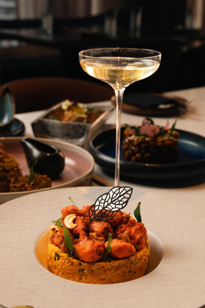 a plate of food and a glass of wine on a table at Radisson Blu Hotel Pune Kharadi in Pune