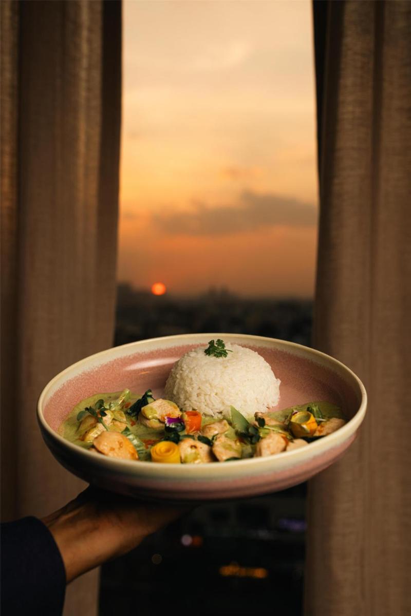 a person holding a bowl of food with rice at Radisson Blu Hotel Pune Kharadi in Pune