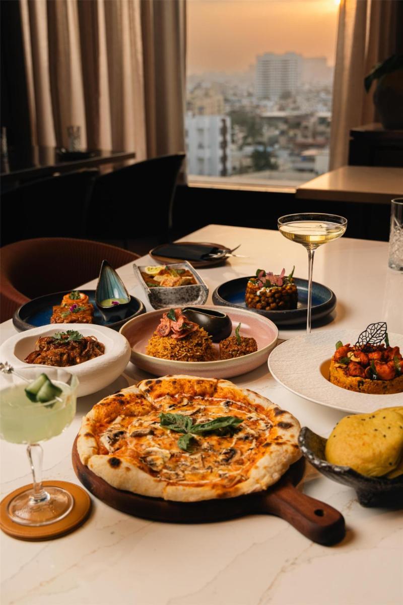 a table with plates of food and a pizza on it at Radisson Blu Hotel Pune Kharadi in Pune