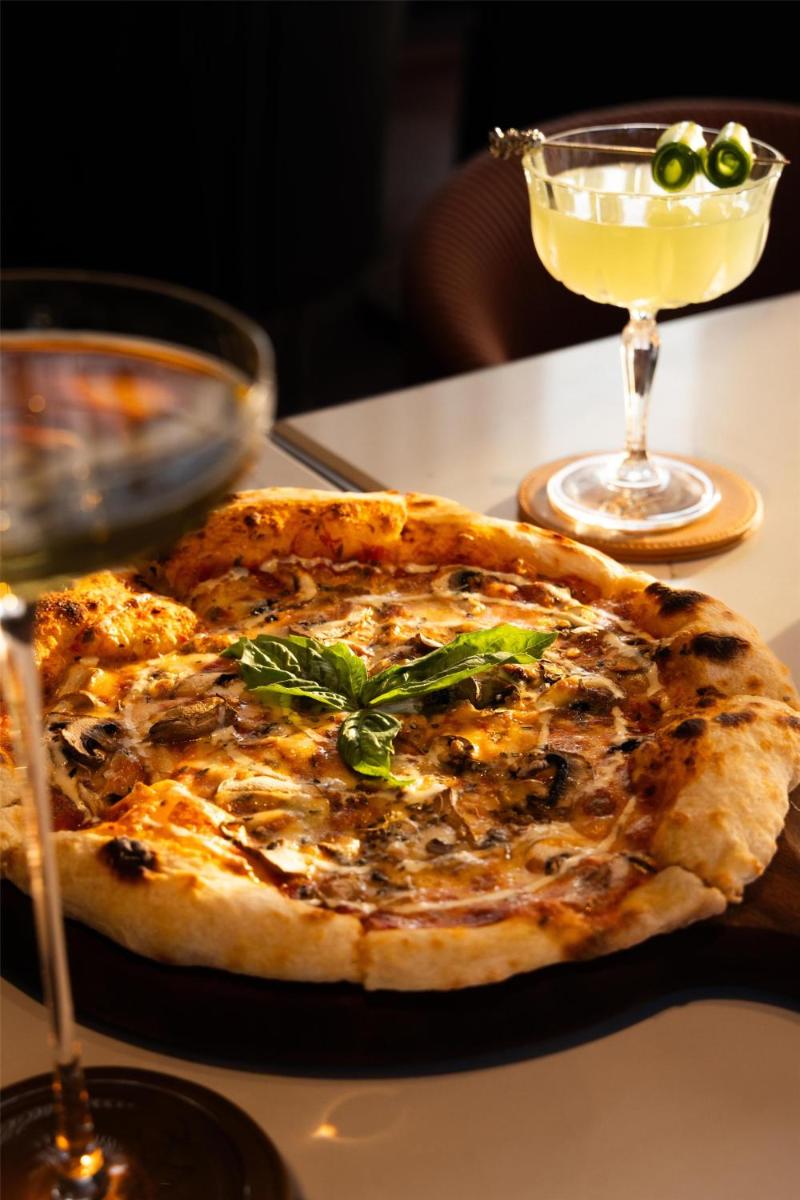 a pizza sitting on a table next to a drink at Radisson Blu Hotel Pune Kharadi in Pune