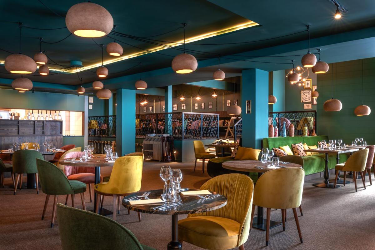 une salle à manger avec des tables, des chaises et des lumières dans l'établissement ILY Hotels & Spa La Rosiere, à La Rosière