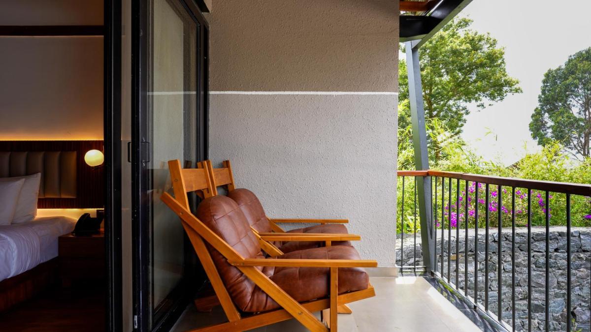 a wooden rocking chair sitting on a balcony at WelcomHeritage Ayatana Ooty in Ooty