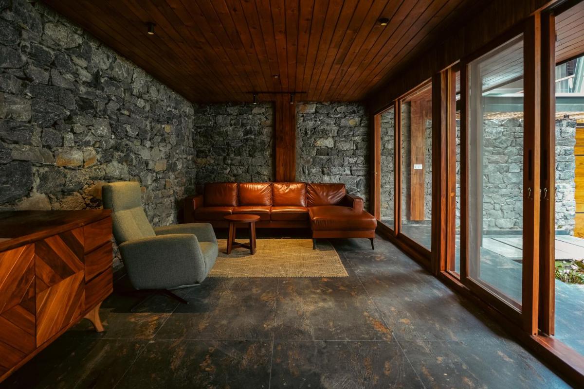 a living room with a leather couch and chairs at WelcomHeritage Ayatana Ooty in Ooty