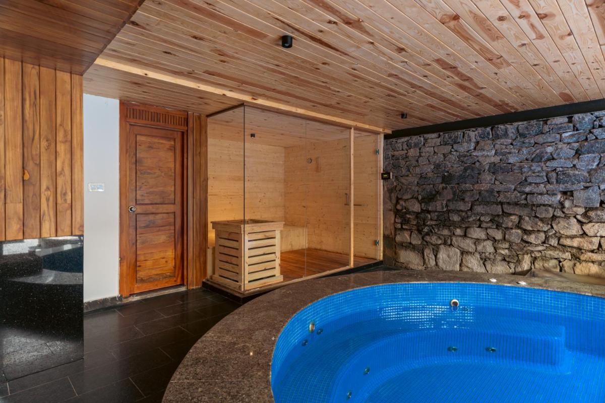 a large blue tub in a room with a stone wall at WelcomHeritage Ayatana Ooty in Ooty