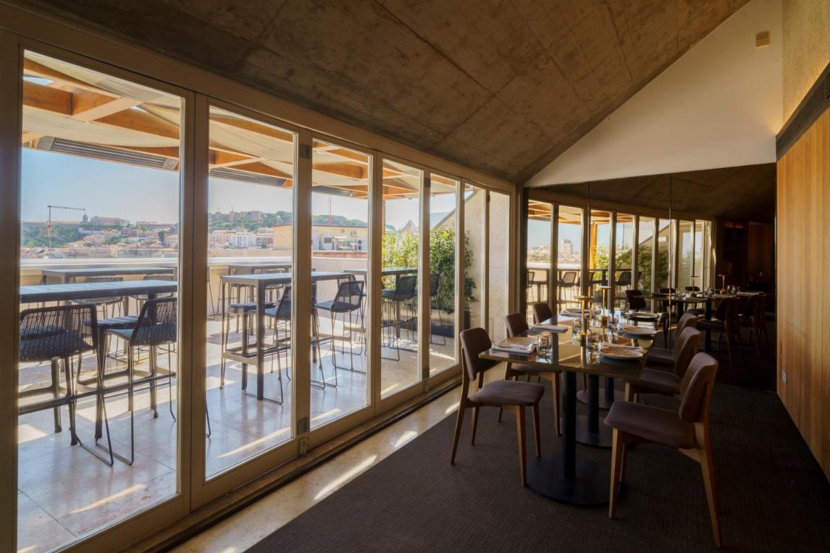 um restaurante com janelas grandes, mesas e cadeiras em Lisboa Pessoa Hotel em Lisboa