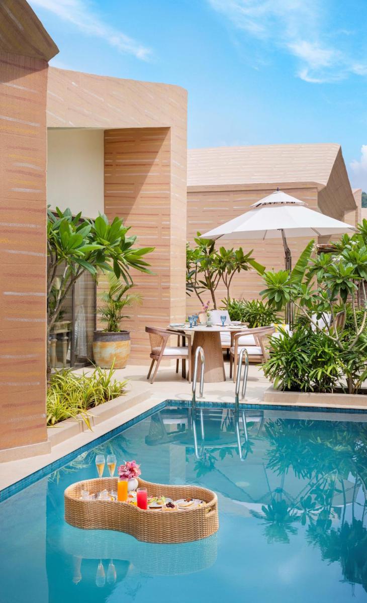 a pool at a resort with a table and chairs at Taj Aravali Resort & Spa Udaipur in Udaipur