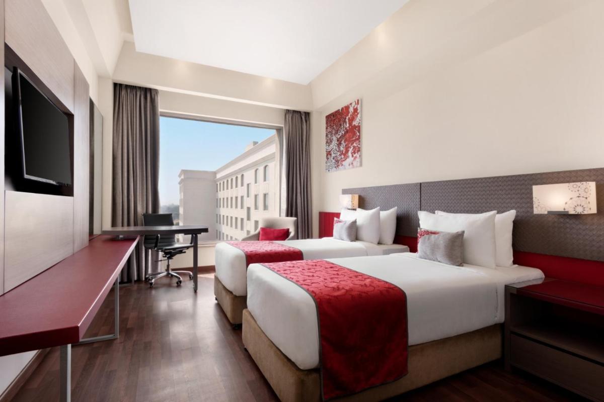 a hotel room with two beds and a desk at Ramada by Wyndham Lucknow Hotel and Convention Center in Lucknow
