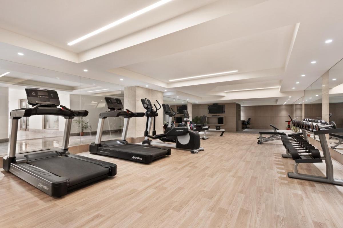 a gym with several treadmills and elliptical machines at Ramada by Wyndham Lucknow Hotel and Convention Center in Lucknow