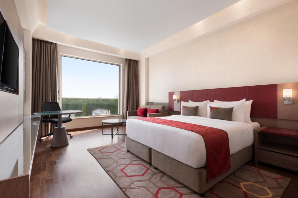 a hotel room with a large bed and a large window at Ramada by Wyndham Lucknow Hotel and Convention Center in Lucknow
