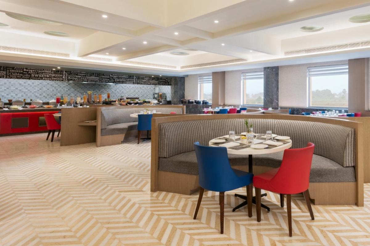 a restaurant with a table and chairs and a bar at Ramada by Wyndham Lucknow Hotel and Convention Center in Lucknow