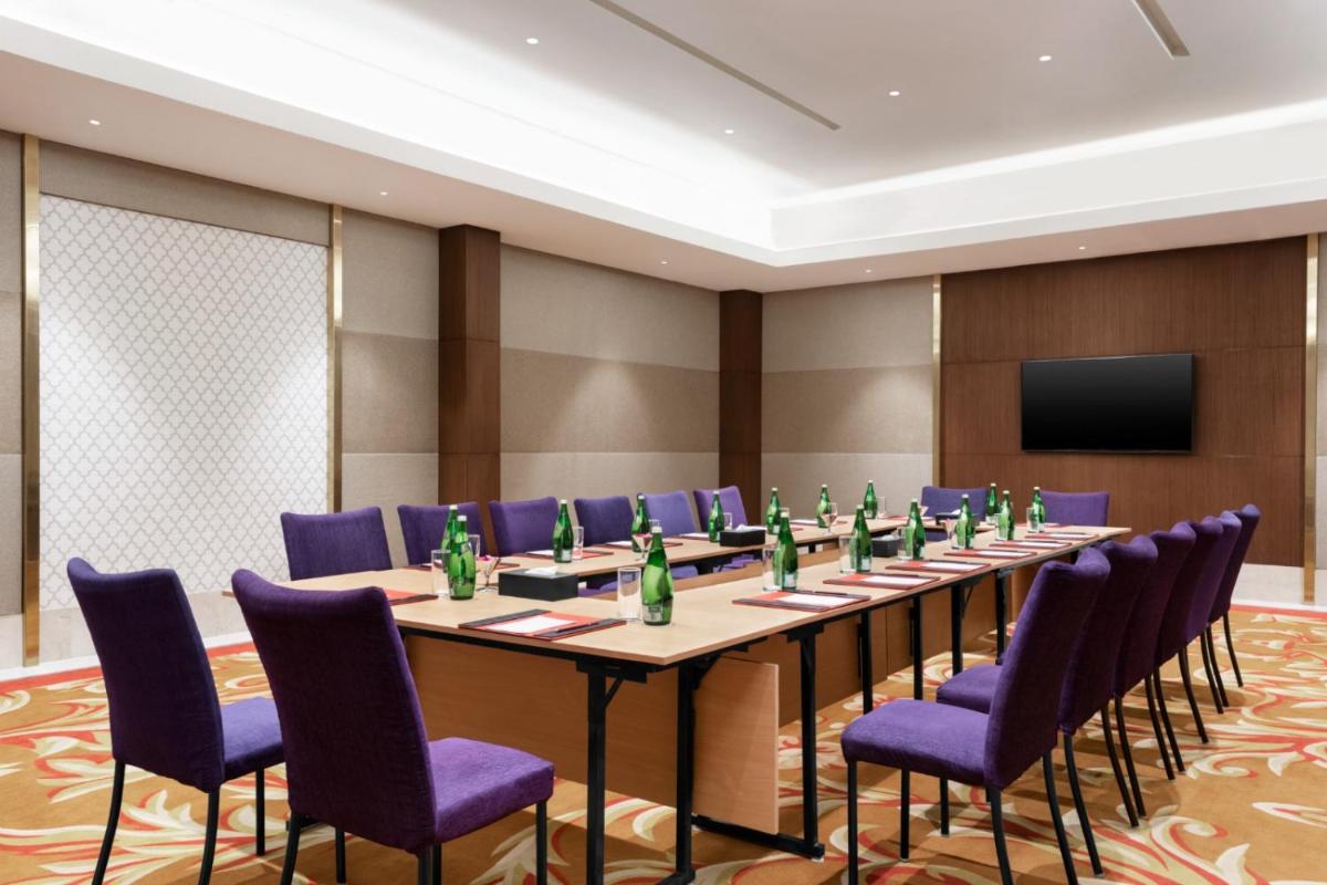 a conference room with a long table and purple chairs at Ramada by Wyndham Lucknow Hotel and Convention Center in Lucknow