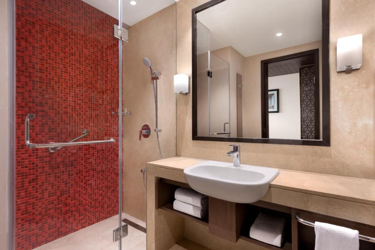 a bathroom with a sink and a shower with a mirror at Ramada by Wyndham Lucknow Hotel and Convention Center in Lucknow
