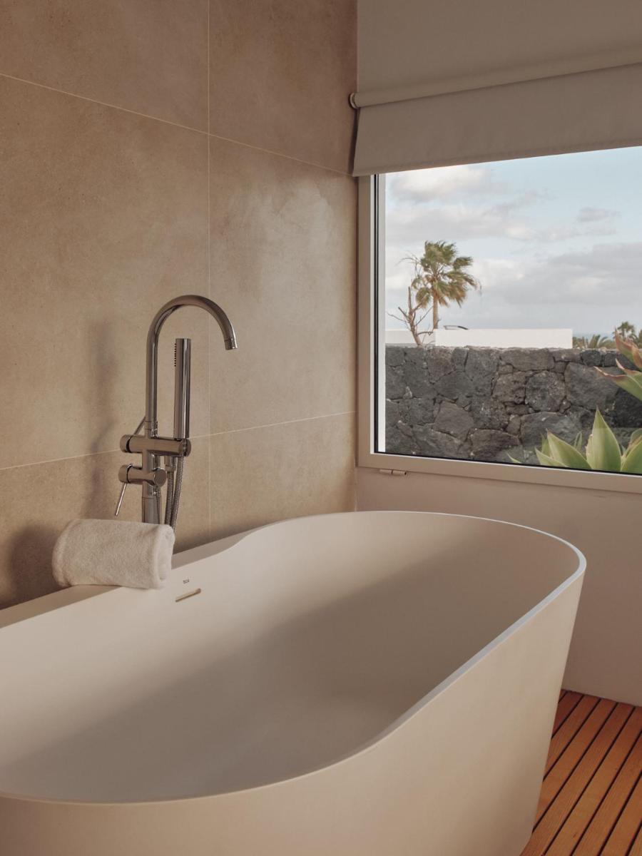 Una bañera blanca en un baño con ventana. en Villas Alondra, en Puerto del Carmen Una bañera blanca en un baño con ventana. en Villas Alondra, en Puerto del Carmen