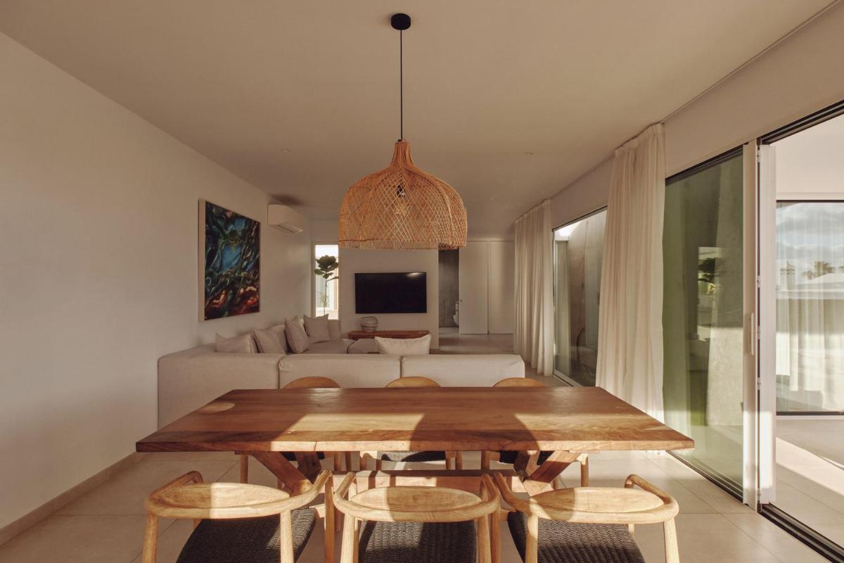 comedor y sala de estar con mesa de madera y sillas en Villas Alondra, en Puerto del Carmen