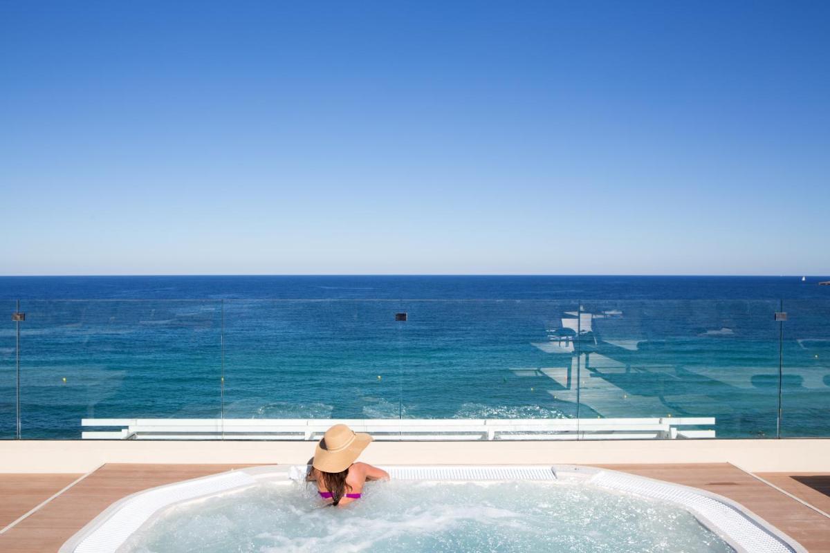 una mujer en un jacuzzi con el océano en el fondo en Hotel Sabina, en Cala Millor