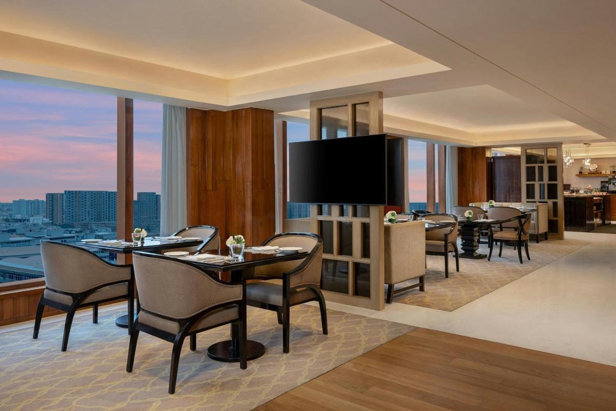 a dining room with tables and chairs and a television at Bengaluru Marriott Hotel Whitefield in Bengaluru