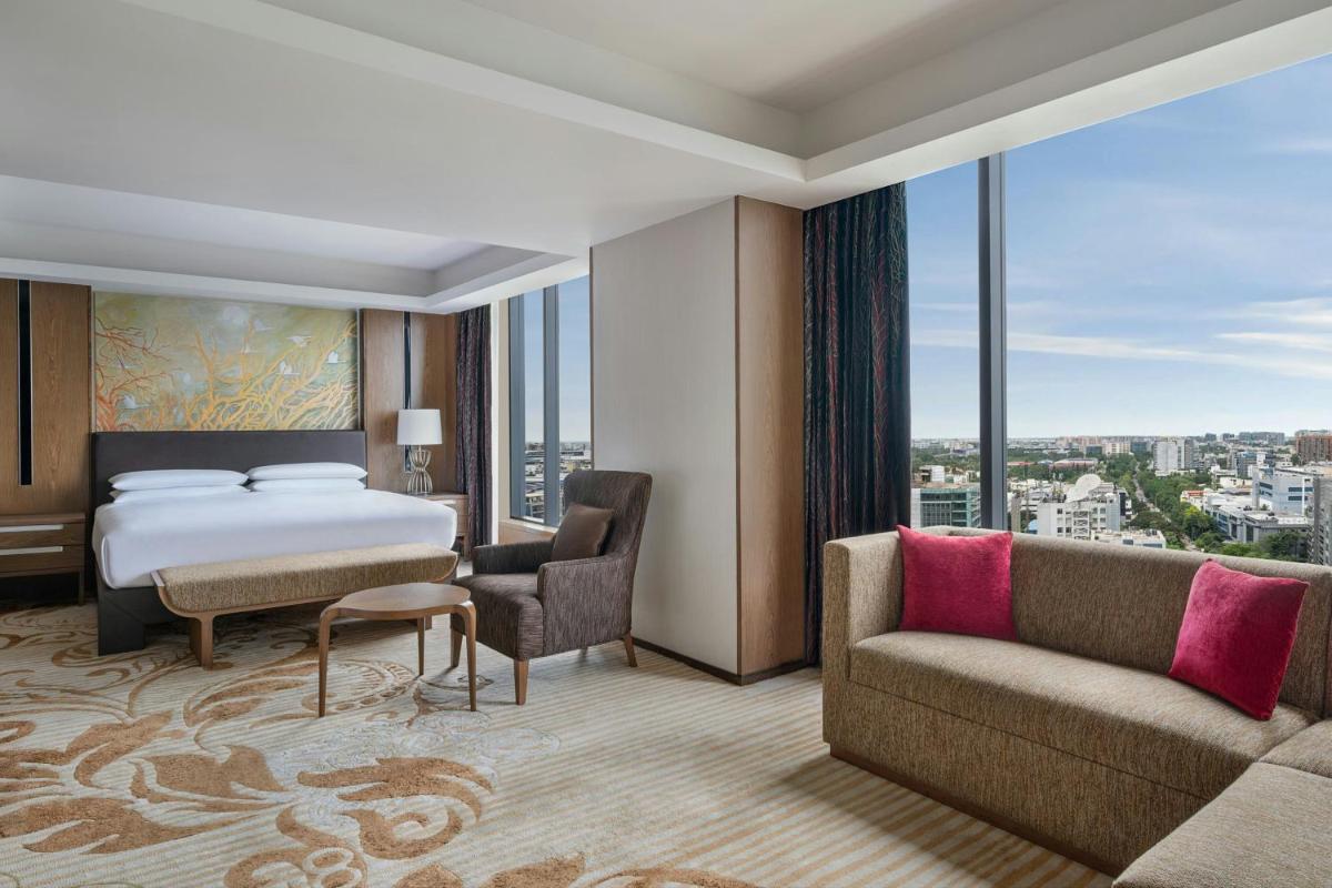 a hotel room with a bed and a couch at Bengaluru Marriott Hotel Whitefield in Bengaluru