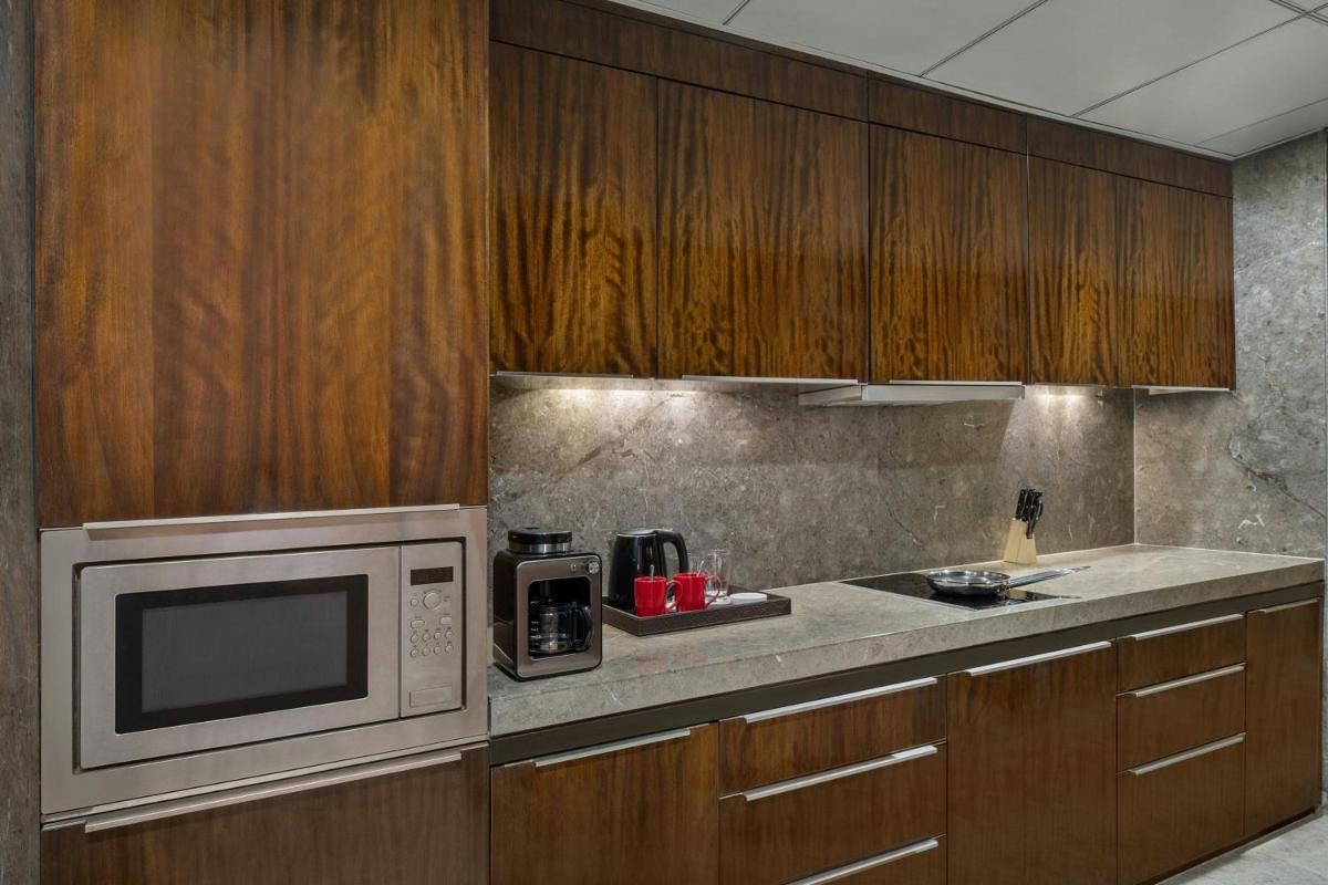 a kitchen with wooden cabinets and a microwave at Bengaluru Marriott Hotel Whitefield in Bengaluru